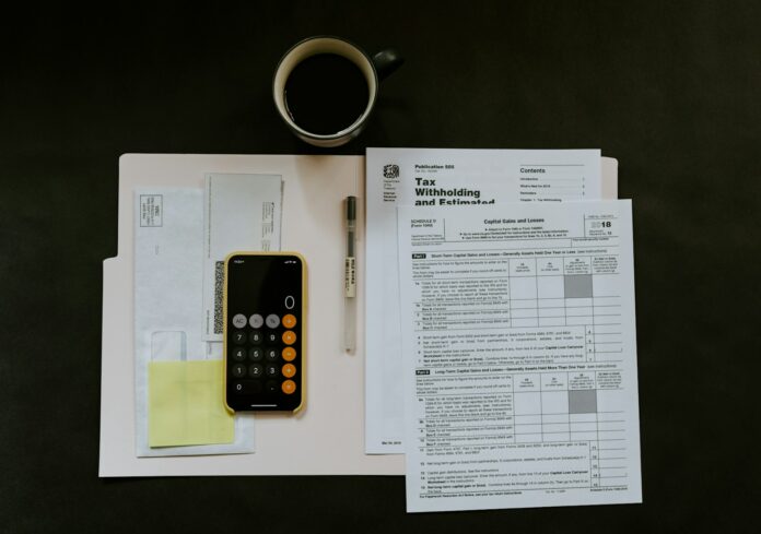 Photo by Kelly Sikkema black Android smartphone near ballpoint pen, tax withholding certificate on top of white folder