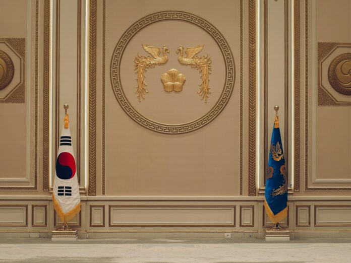 Photo by Clark Gu a room with two flags and a coat of arms on the wall