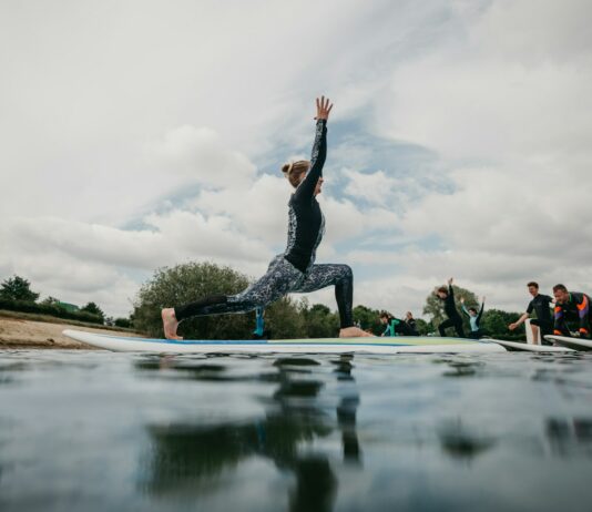 여름철 건강한 스트레칭 루틴 woman in black tank top and black leggings doing yoga on blue yoga mat on water