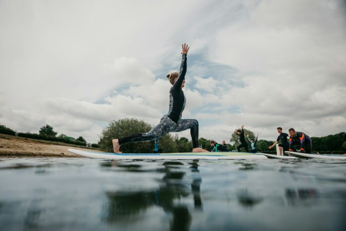 Photo by Joppe Spaa woman in black tank top and black leggings doing yoga on blue yoga mat on water
