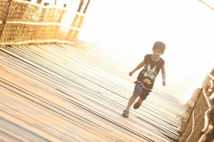 Photo by Istiaque Emon boy walking on brown wooden bridge