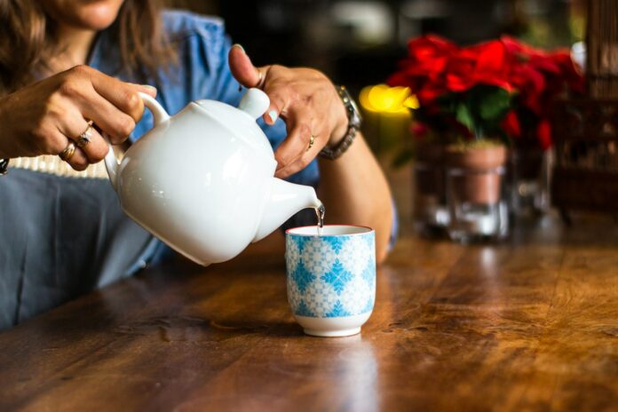 Photo by Louis Hansel unknown person holding white ceramic kettle