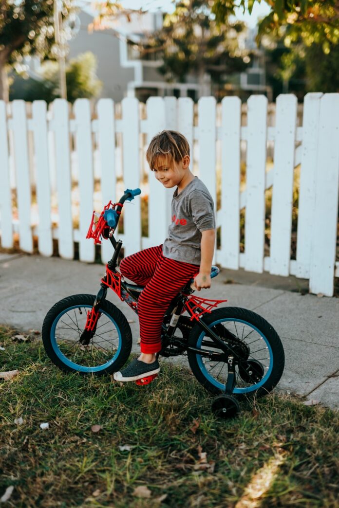 Photo by Nathan Dumlao girl in red and black bicycle suit standing beside white wooden fence during daytime