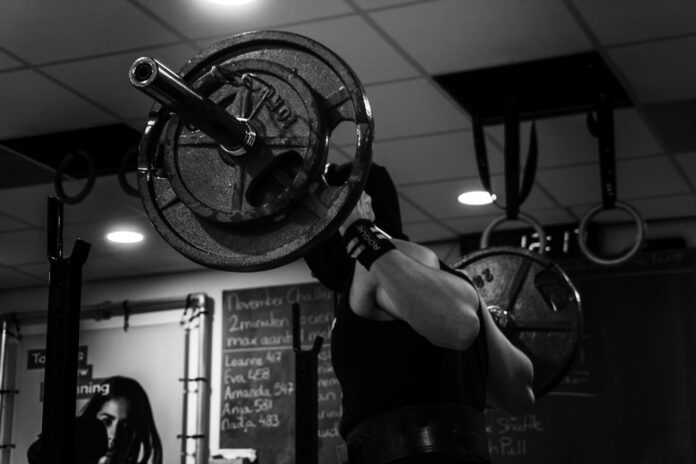 Photo by Cindy Koops grayscale photo of man lifting barbell