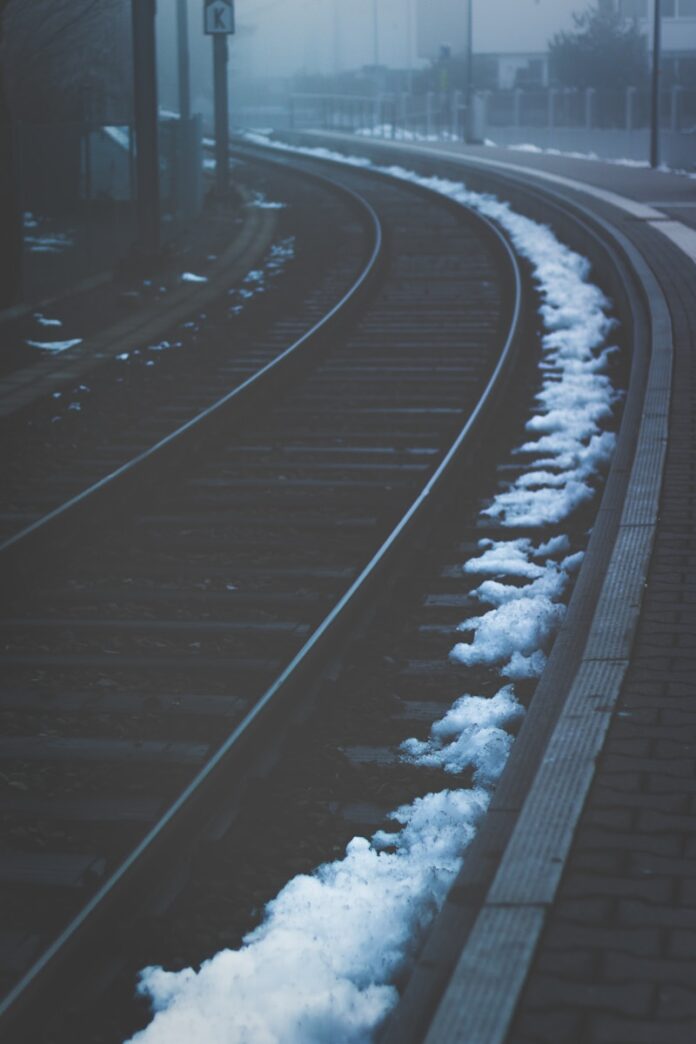 Photo by Basil Lade low light photography of train rails under foggy sky