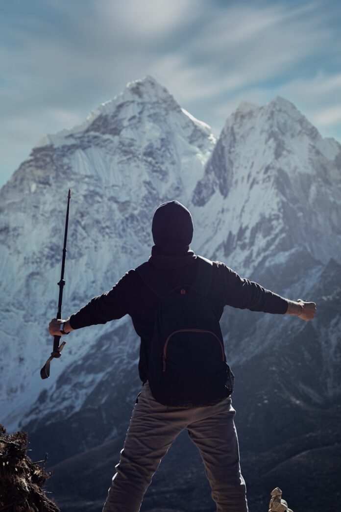 Photo by Pulkit Pithva a man holding a rifle while standing on top of a mountain