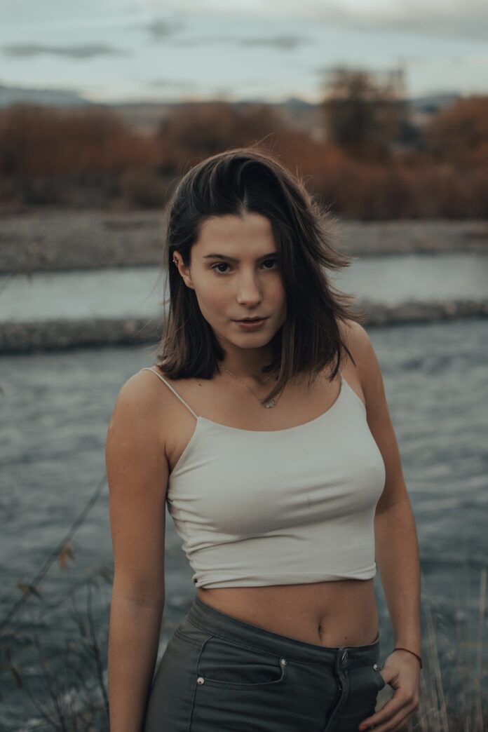 woman in white tank top standing near body of water during daytime